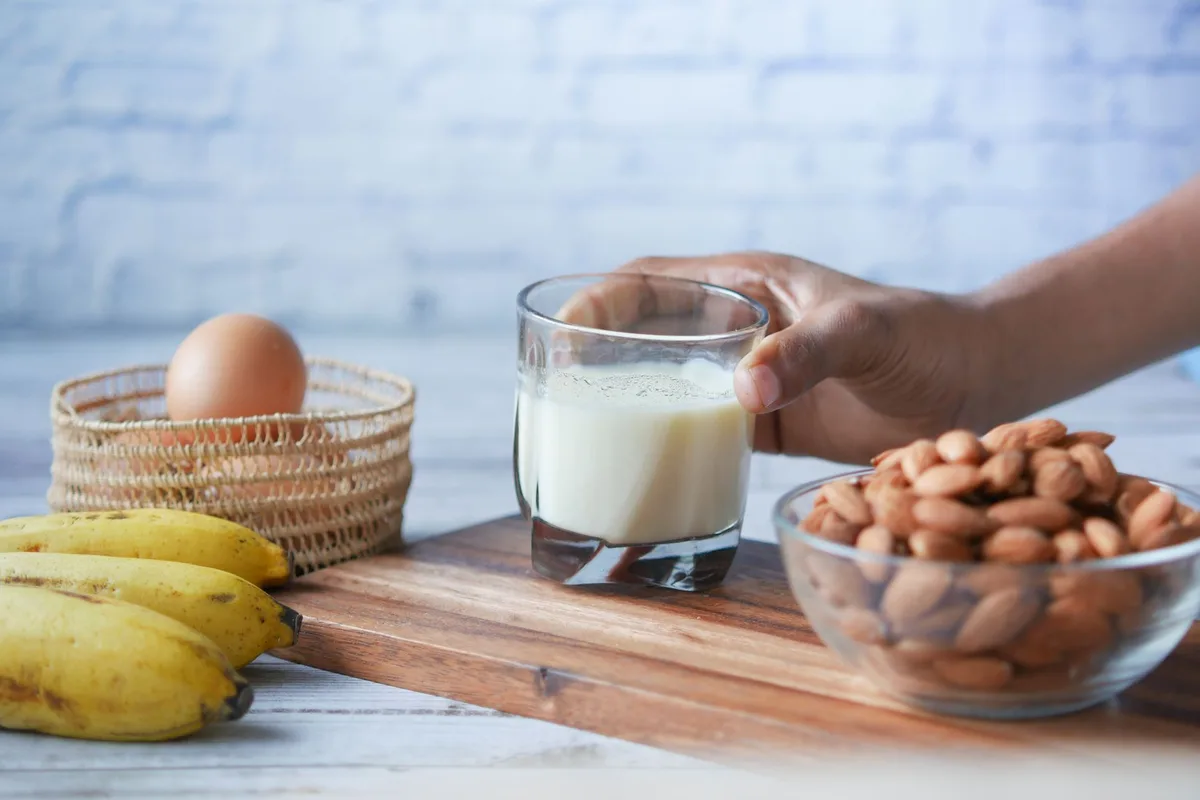 Aliments riches en protéines : œufs, yaourt grec, poisson et noix sur une table