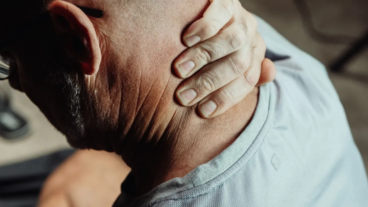 Personne tenant son dos ou sa tête, exprimant une douleur ou une gêne physique.