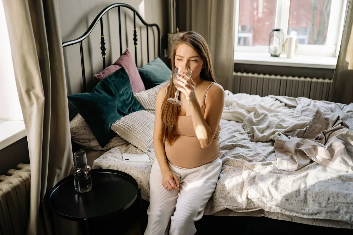 Femme enceinte buvant un verre d'eau le matin pour faciliter le transit