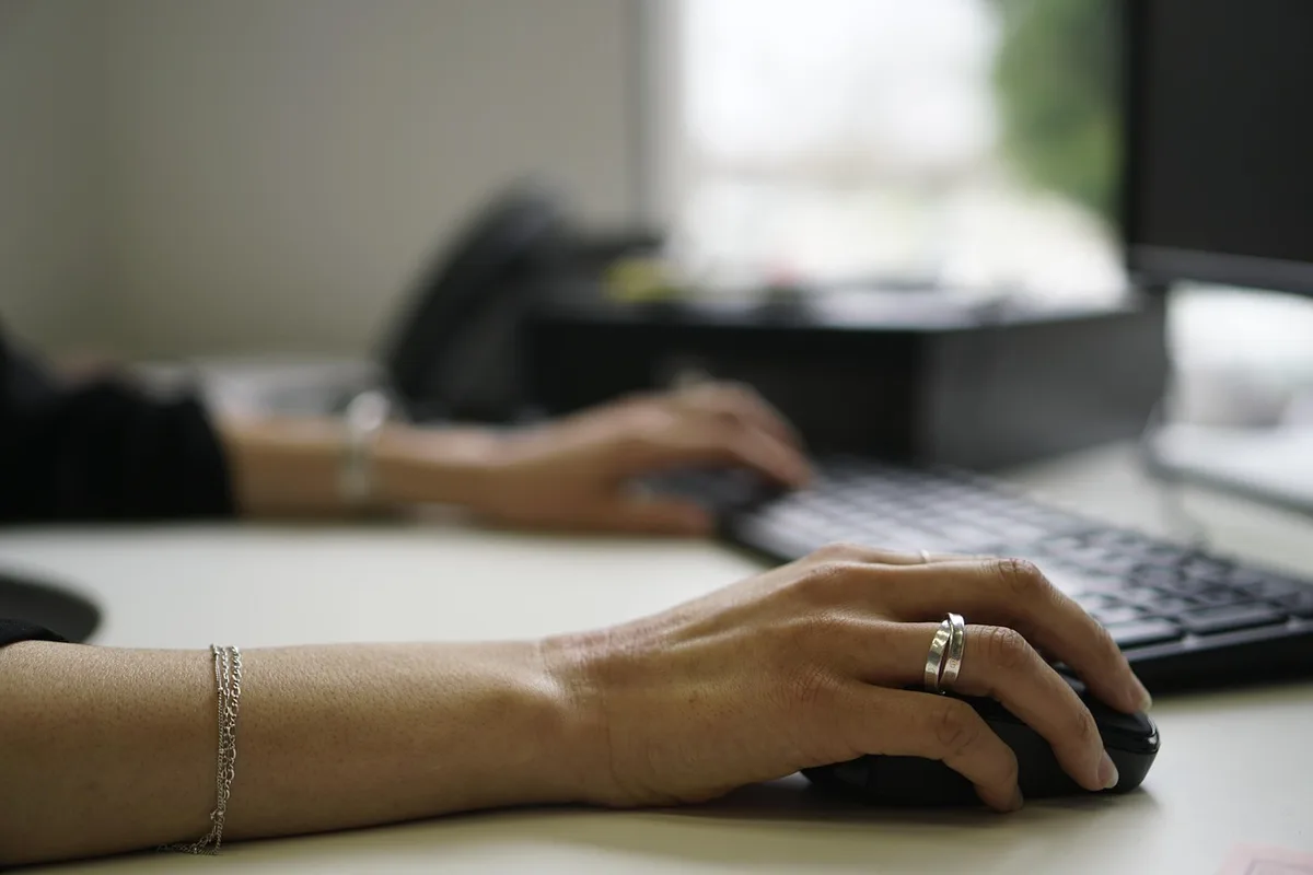 Mains répétitives tapant au clavier sur un bureau